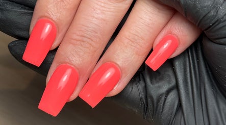 Vibrant coral acrylic nails at CXM Nails, Bangor, Northern Ireland, GB, glowing under salon light.