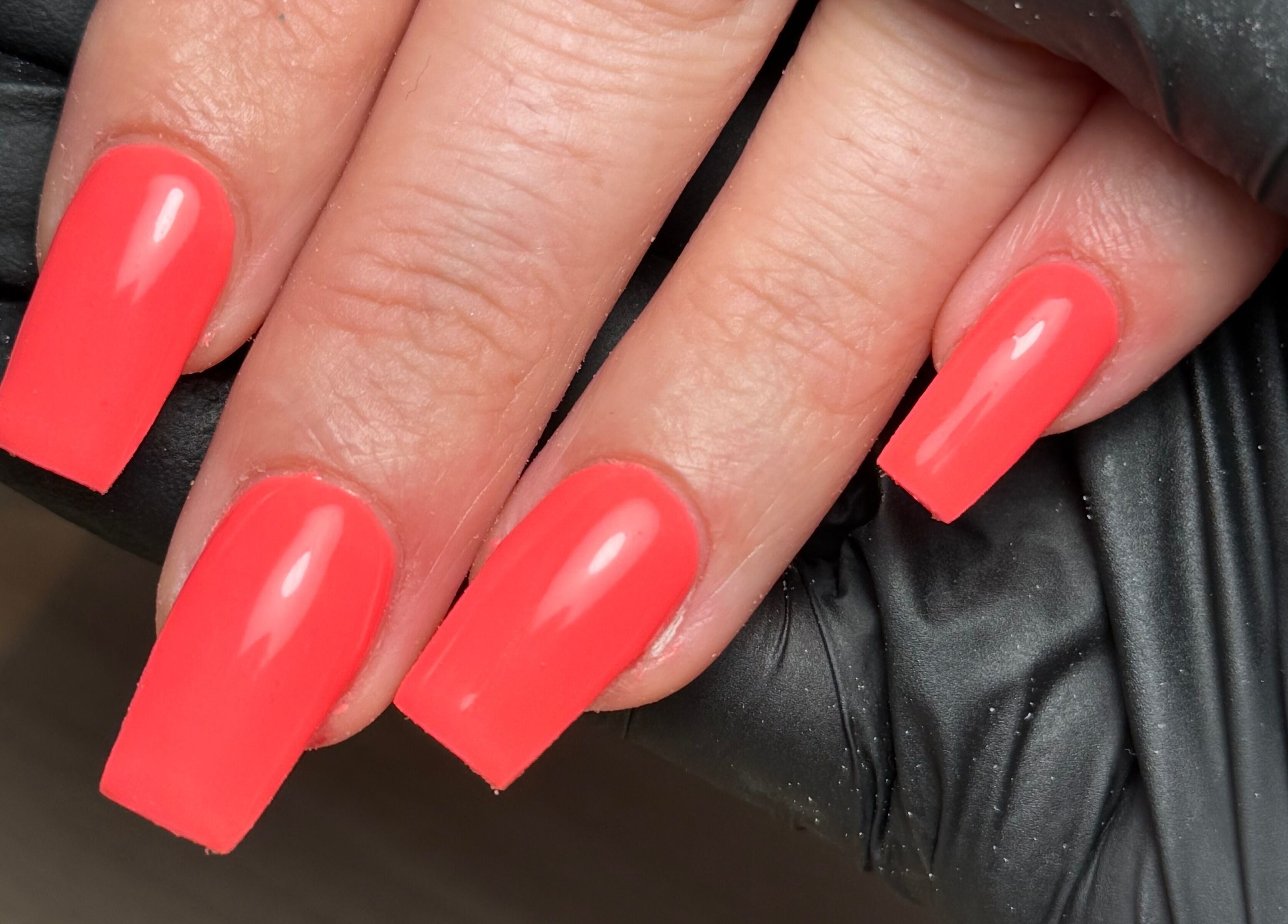 Bright coral nails at CXM Nails in Bangor, Northern Ireland, GB, showcase expert manicure skills.