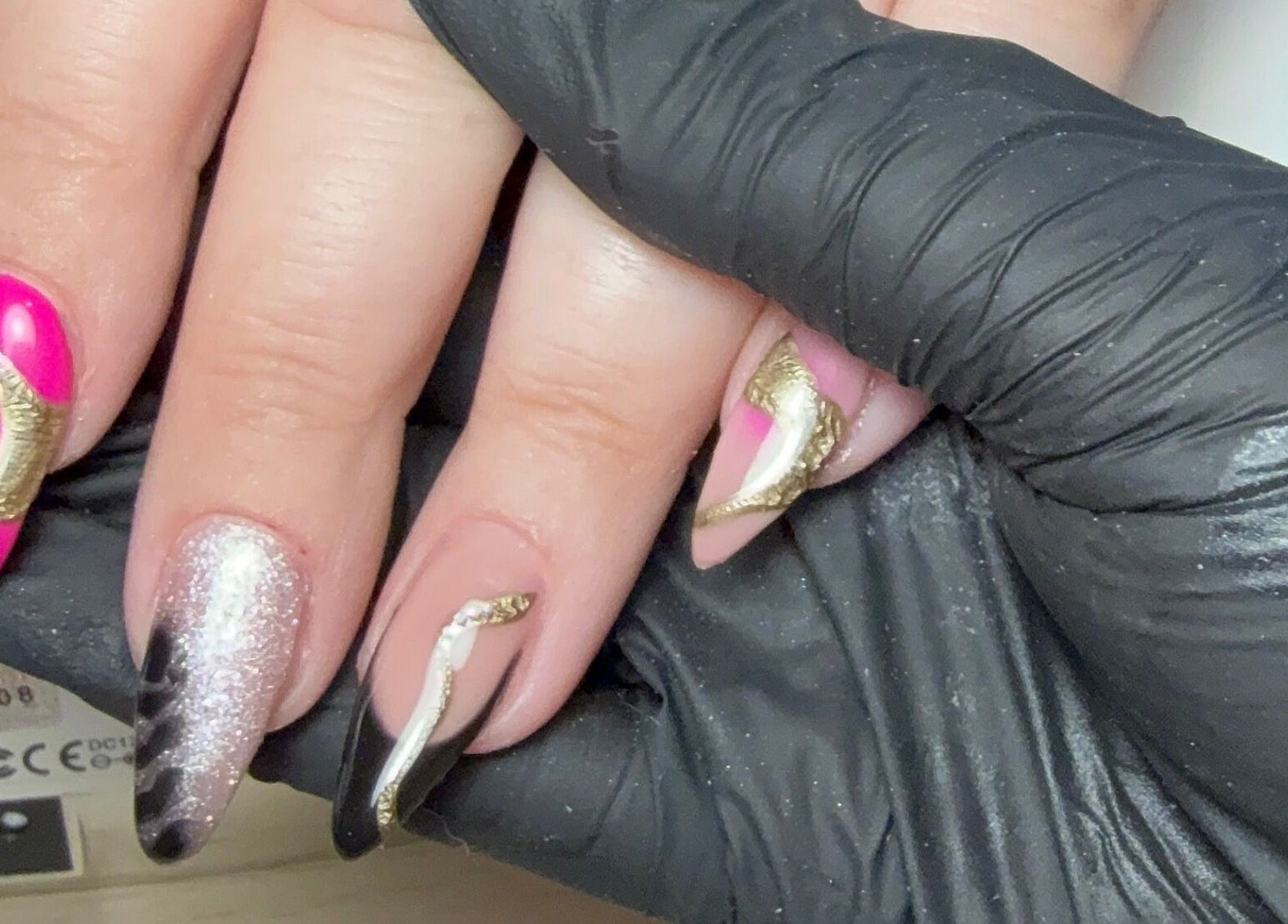 Stylish nail art at CXM Nails in Bangor, Northern Ireland, GB with a vibrant pink and gold design.