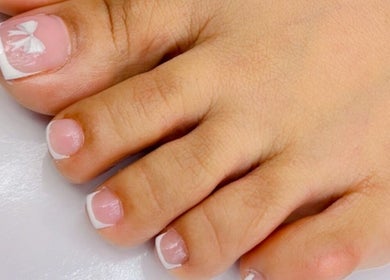 French pedicure with white bow detail at Xio’s Nails in Greensboro, North Carolina, US.