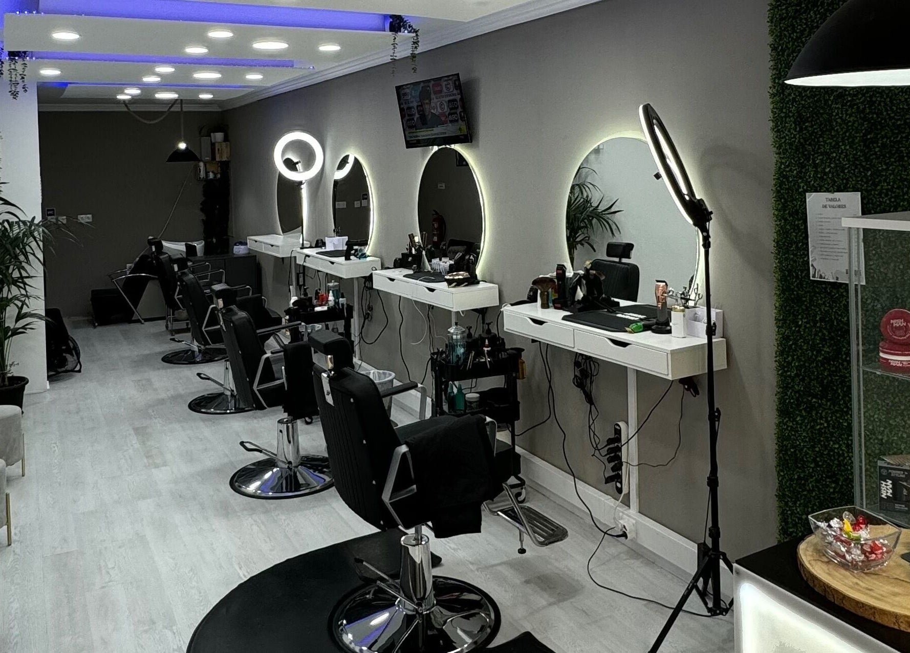 Interior moderno da Unique Barbershop em Estoril, Lisboa, PT, com cadeiras de couro e espelhos iluminados.