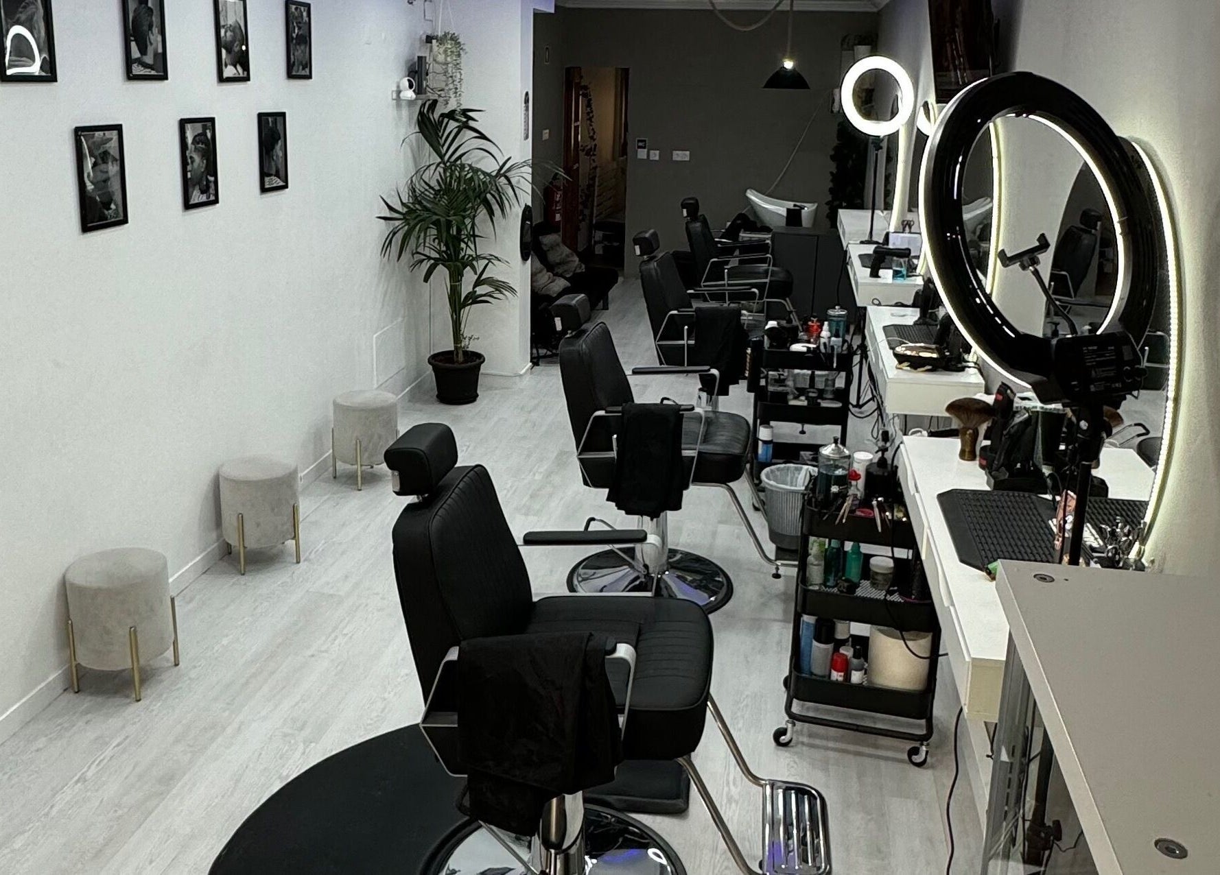 Interior moderno no Unique Barbershop, Estoril, Lisboa, PT, com cadeiras de barbeiro e luzes LED.