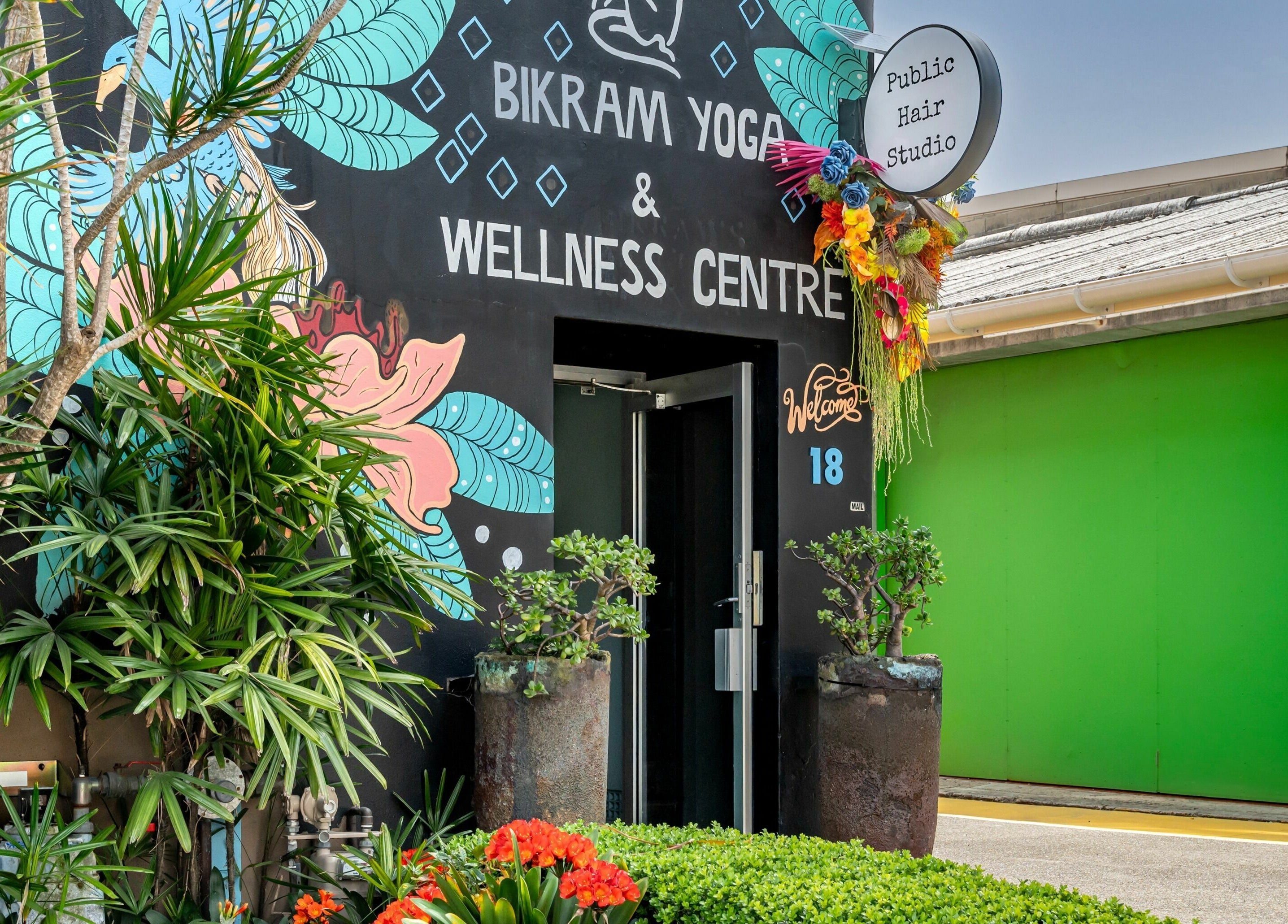 Entrance of Public Hair Studio in Brookvale, NSW, AU with lush plants and colorful mural.