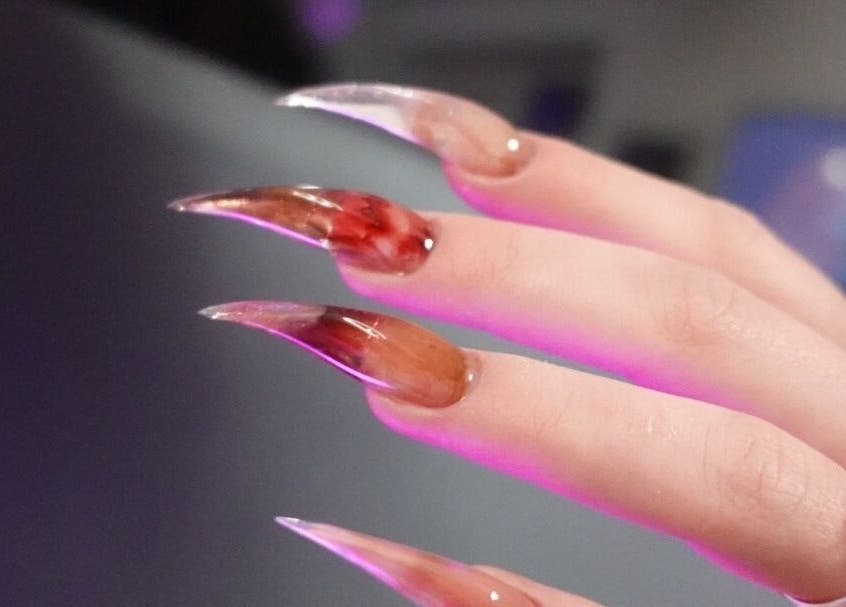 Stiletto-Nageldesign bei VG Beauty Center in Aschheim, Bayern, DE, mit rotem und braunem Farbverlauf.