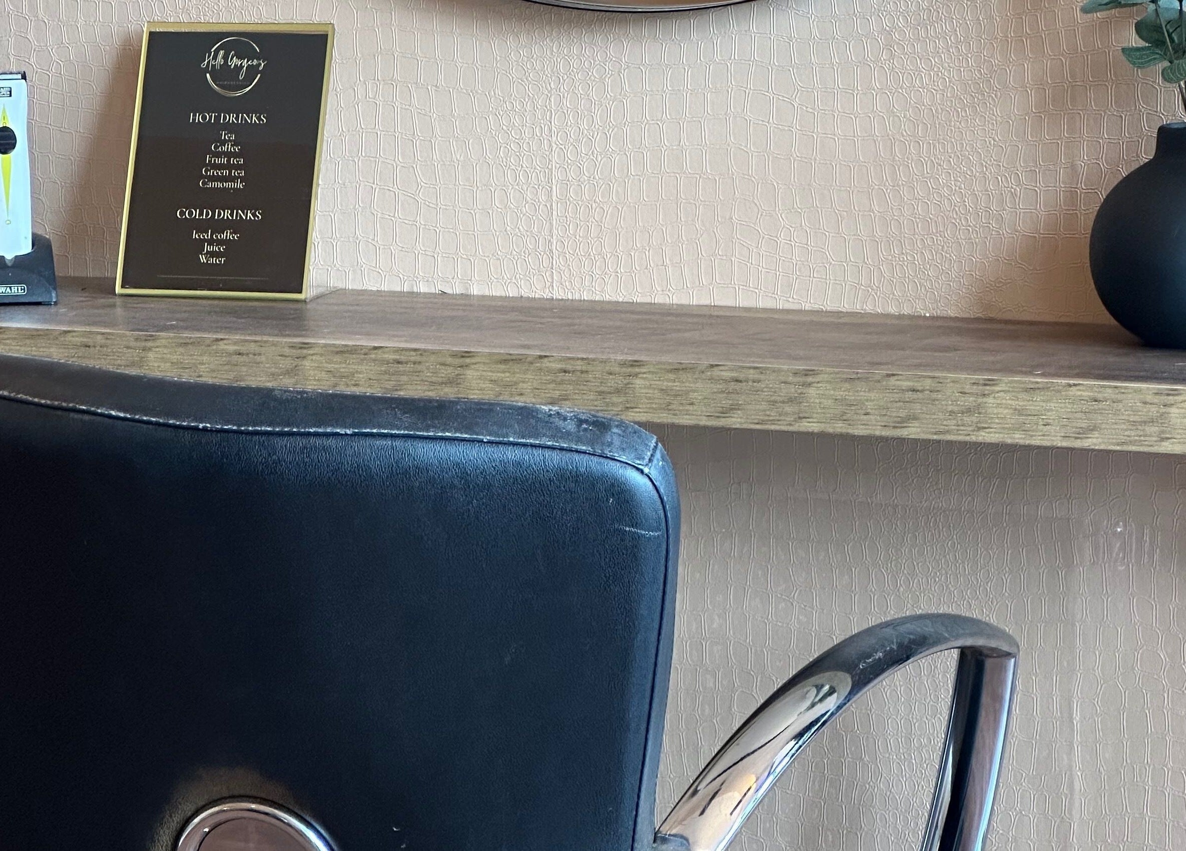 Hello gorgeous Hairdressing, London, England, GB. Stylish salon chair with a wooden shelf and vase decor.