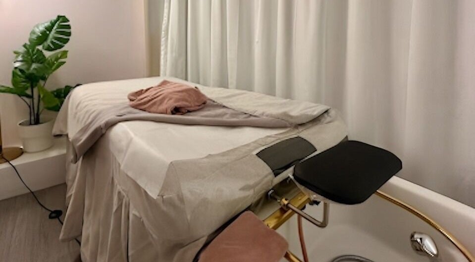 Cozy treatment room at Le Beauty, New York, New York, US with a massage table and lush plant.