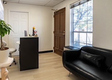 Elegant reception area at UM Beauty Studio, San Jose, California, US with sleek black couch and potted plant.