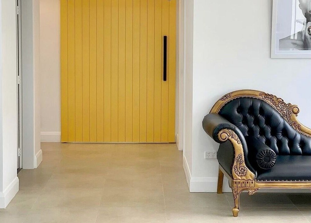 Elegant black and gold sofa at Chiara House of Hair, Warrawong, NSW. Stylish yellow door enhances salon's chic interior.