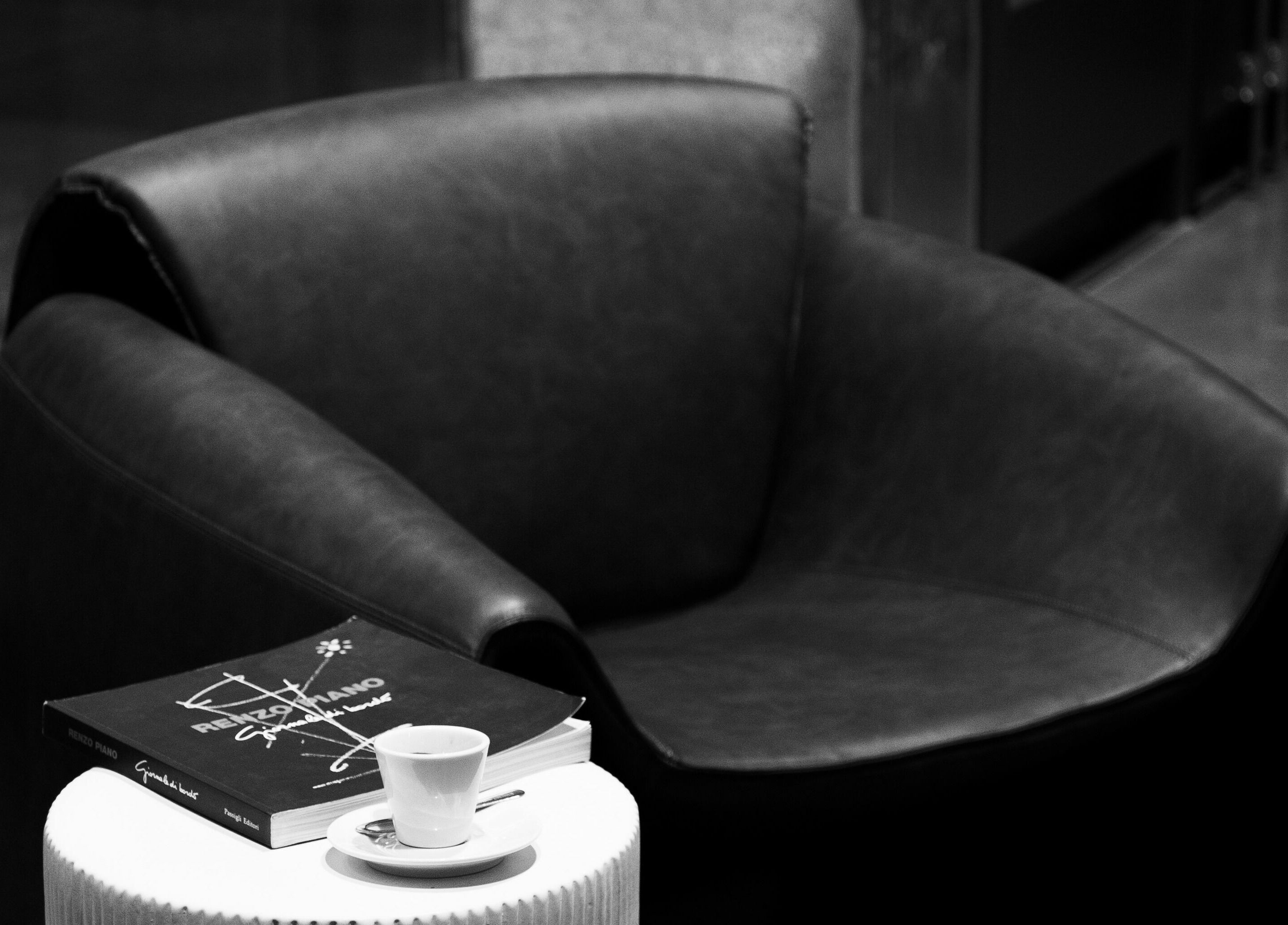Modern black leather chair with a book and espresso at 011 Italian Grooming DIFC, Dubai, Dubai, AE.