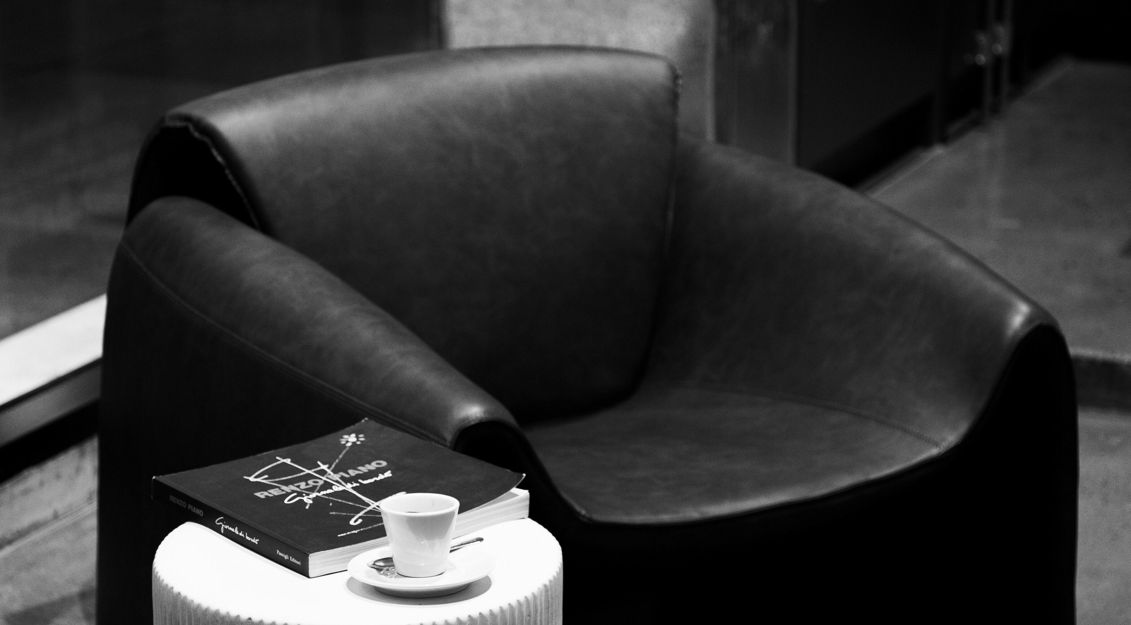 Modern black leather chair with a book and espresso at 011 Italian Grooming DIFC, Dubai, Dubai, AE.