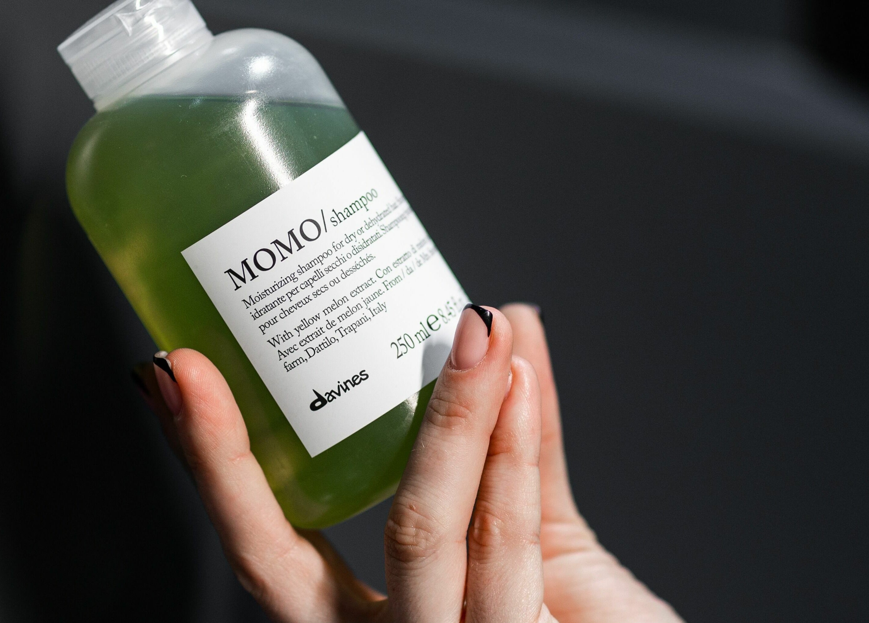 Hand holding a Momo shampoo bottle at 011 Italian Grooming DIFC, Dubai, Dubai, AE.