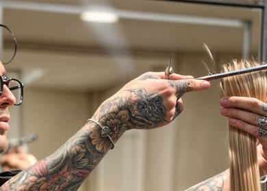 Peluquero con tatuajes corta cabello en ATICA Salón, Madrid, Comunidad De Madrid, ES.