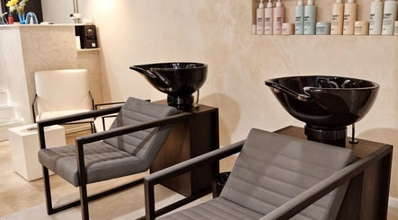 Área de lavado en ATICA Salón, Madrid, Comunidad De Madrid, ES, mostrando sillas modernas y lavabos negros.