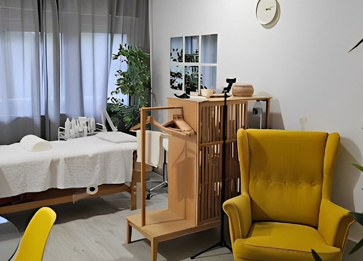 Sala de bem-estar acolhedora em Daniela Dos Santos, Lisboa, PT, com cadeira amarela e mesa de massagem.