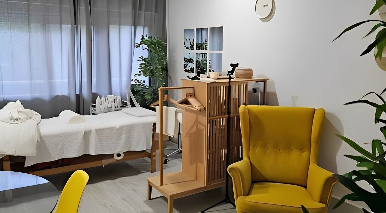Sala de bem-estar acolhedora em Daniela Dos Santos, Lisboa, PT, com cadeira amarela e mesa de massagem.
