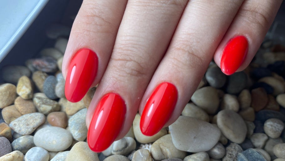Red manicured nails on pebbles at Glamicious nails by Katia, L-imġarr, MT.