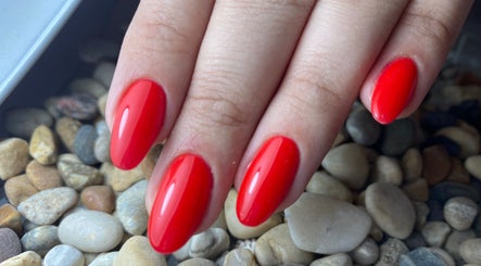 Red manicured nails on pebbles at Glamicious nails by Katia, L-imġarr, MT.