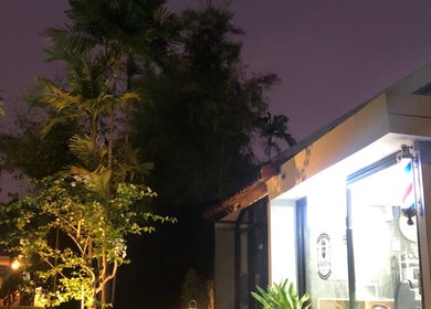 Drixs Barber and Hairstudio in Bali, Bali, ID, illuminated at dusk with palm trees and a glowing barber's pole.