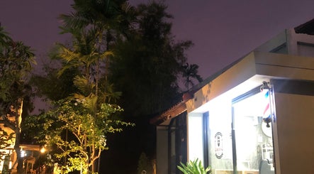 Drixs Barber and Hairstudio in Bali, Bali, ID, illuminated at dusk with palm trees and a glowing barber's pole.