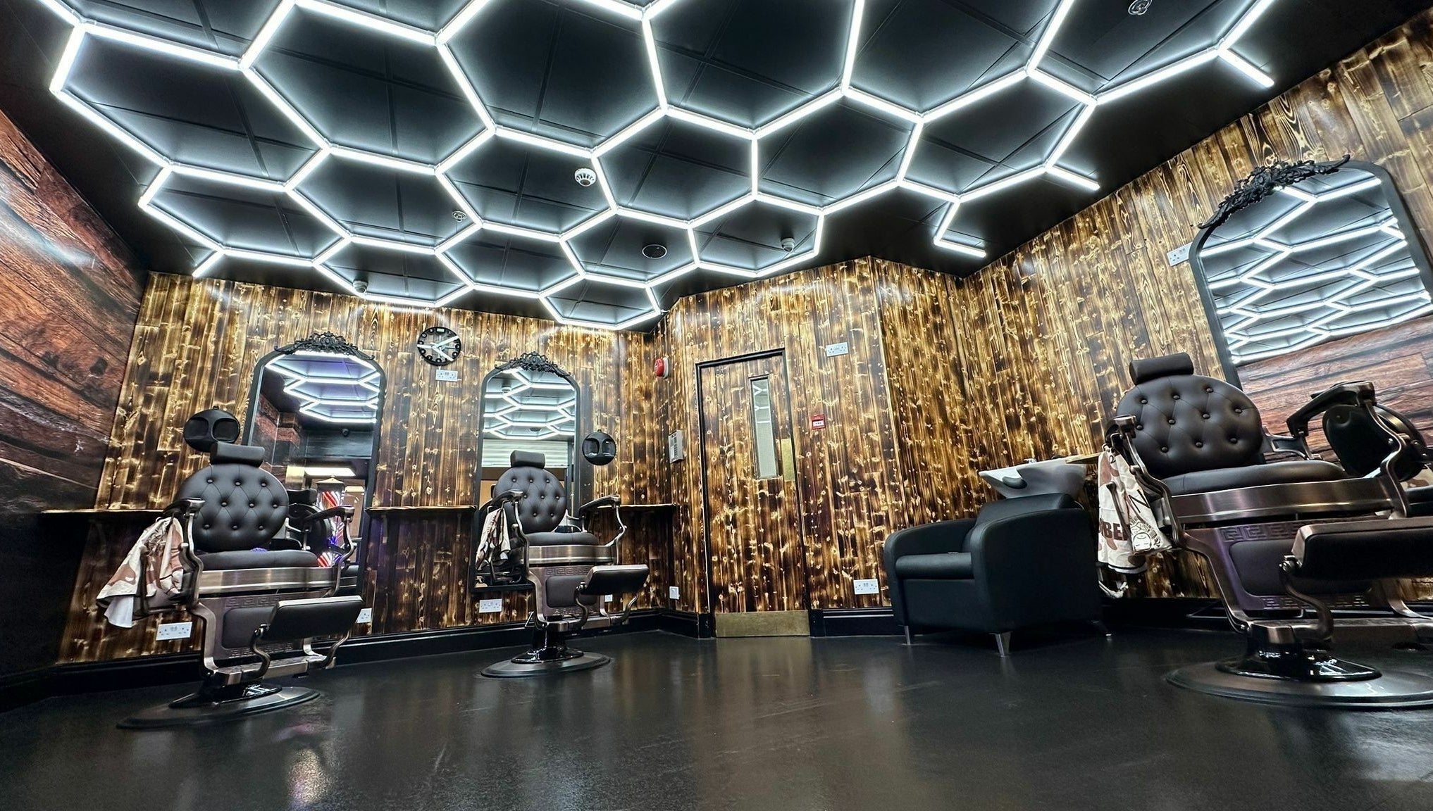 Modern barber shop interior at Eldon Barbers, Newcastle upon Tyne, England, GB with sleek chairs and hexagon lighting.