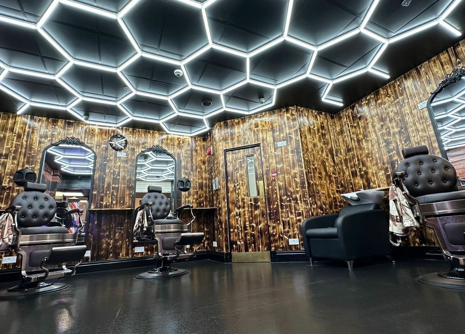 Modern barber shop interior at Eldon Barbers, Newcastle upon Tyne, England, GB with sleek chairs and hexagon lighting.