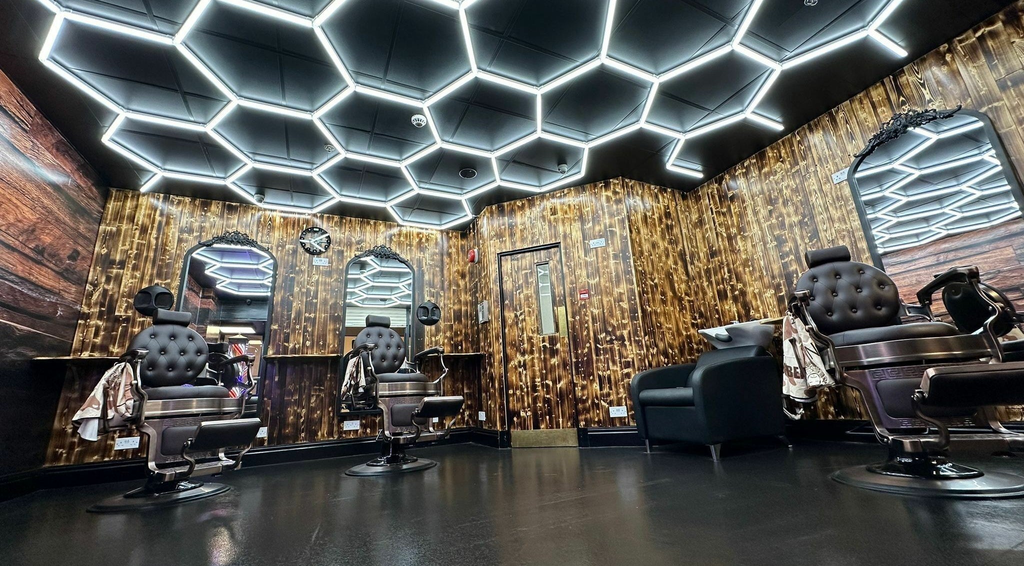 Modern barber shop interior at Eldon Barbers, Newcastle upon Tyne, England, GB with sleek chairs and hexagon lighting.