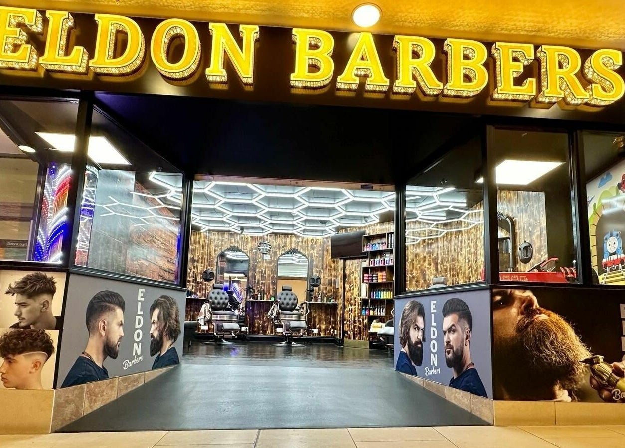 Eldon Barbers storefront with illuminated sign and modern interior in Newcastle upon Tyne, England, GB.