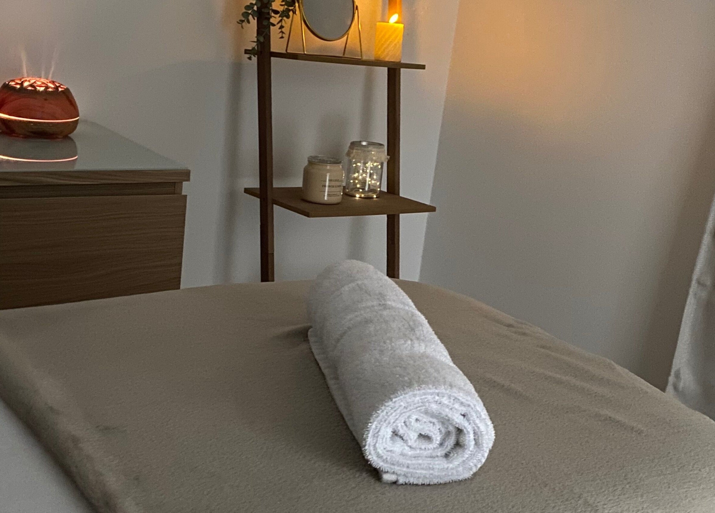 Ambiance relaxante au Le Boudoir De Camille, Troyes, Grand Est, FR. Un lit de spa prêt avec une serviette roulée.