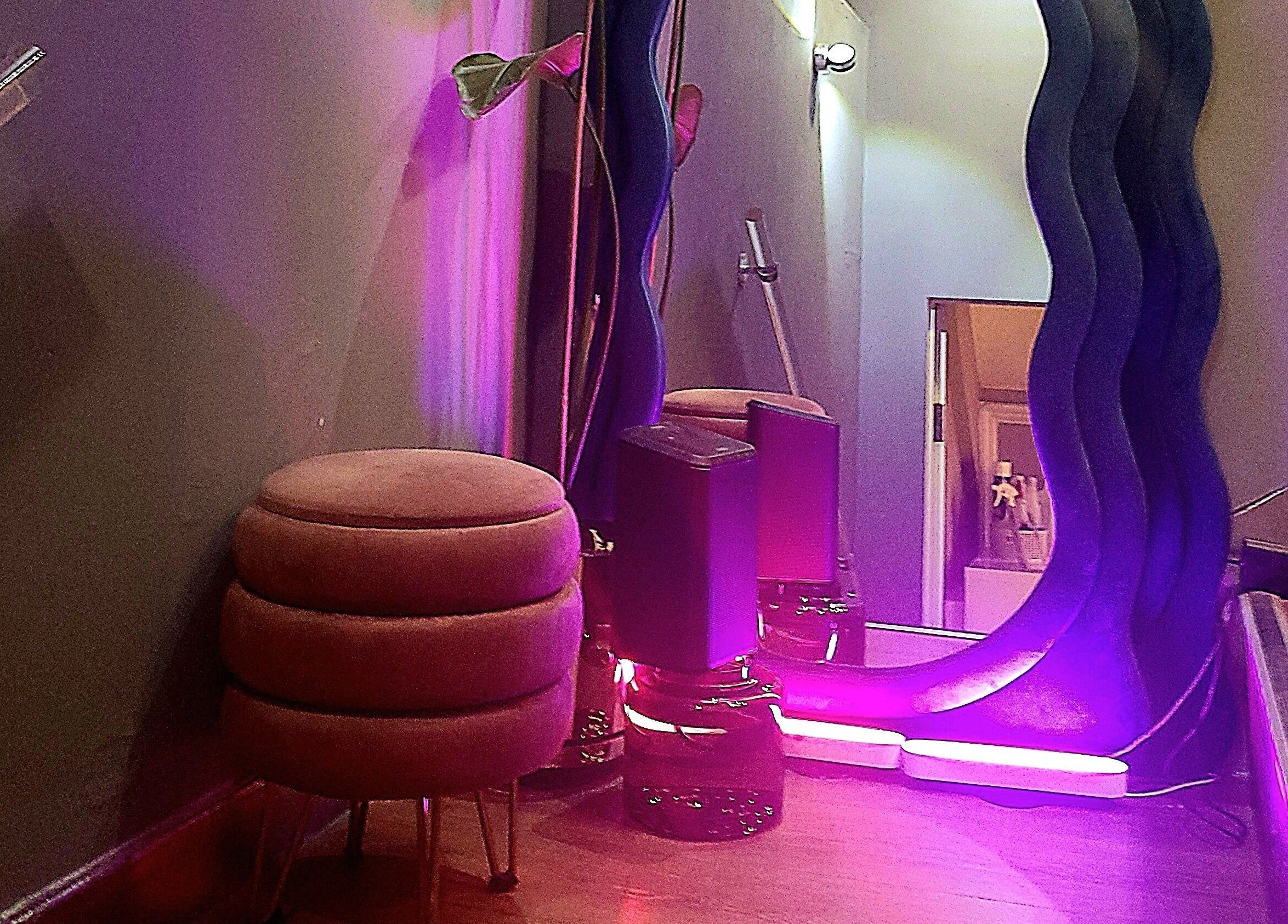 Cozy corner at Crazylong Nail Studio, London, with pink lighting and modern decor creating a relaxing ambiance.