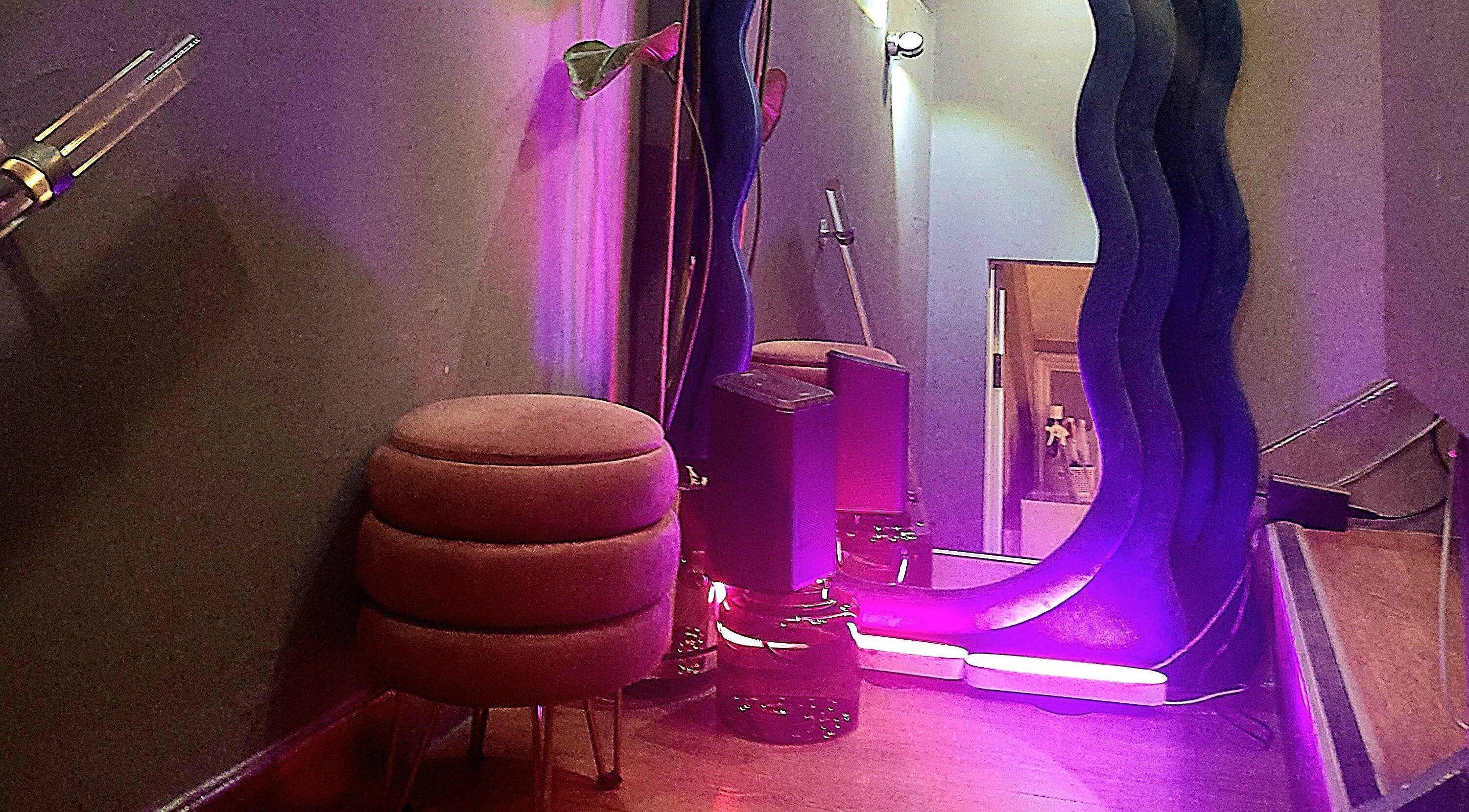 Cozy corner at Crazylong Nail Studio, London, with pink lighting and modern decor creating a relaxing ambiance.