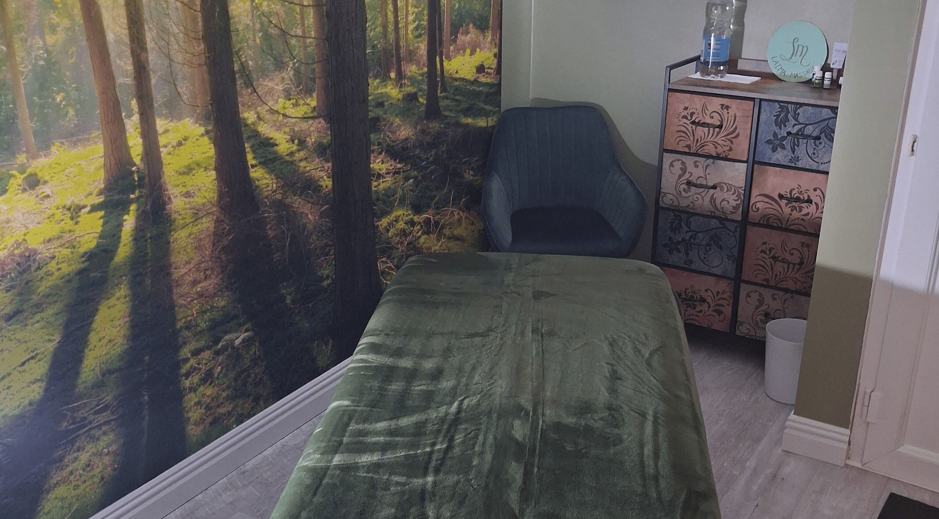 Calm massage room at Laima Massage, Bletchley, England with forest-themed decor.