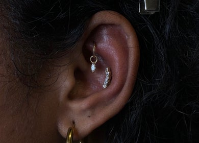 Elegant ear piercings at The Needle Room, London, England, GB, featuring gold and diamond jewelry.