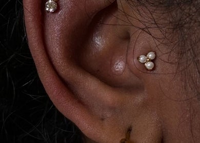Close-up of ear piercings with pearl and diamond studs at The Needle Room, London, England, GB.