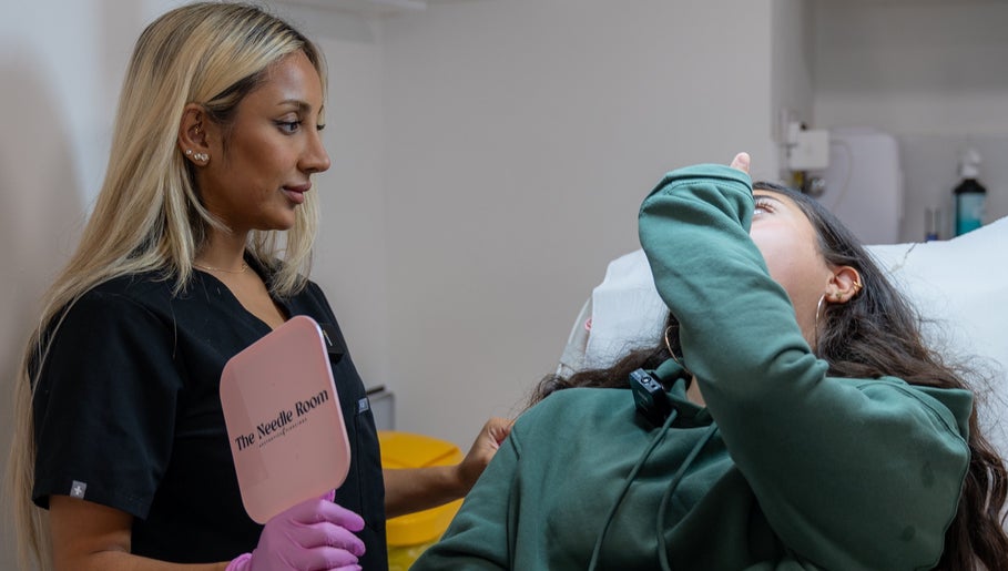 Practitioner consulting client at The Needle Room, London, England, GB, holding branded mirror.