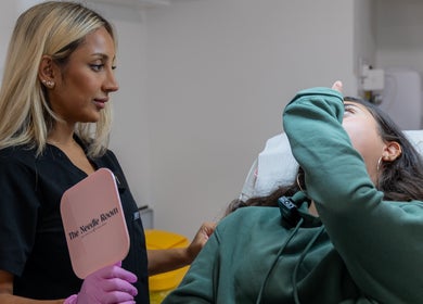 Practitioner consulting client at The Needle Room, London, England, GB, holding branded mirror.
