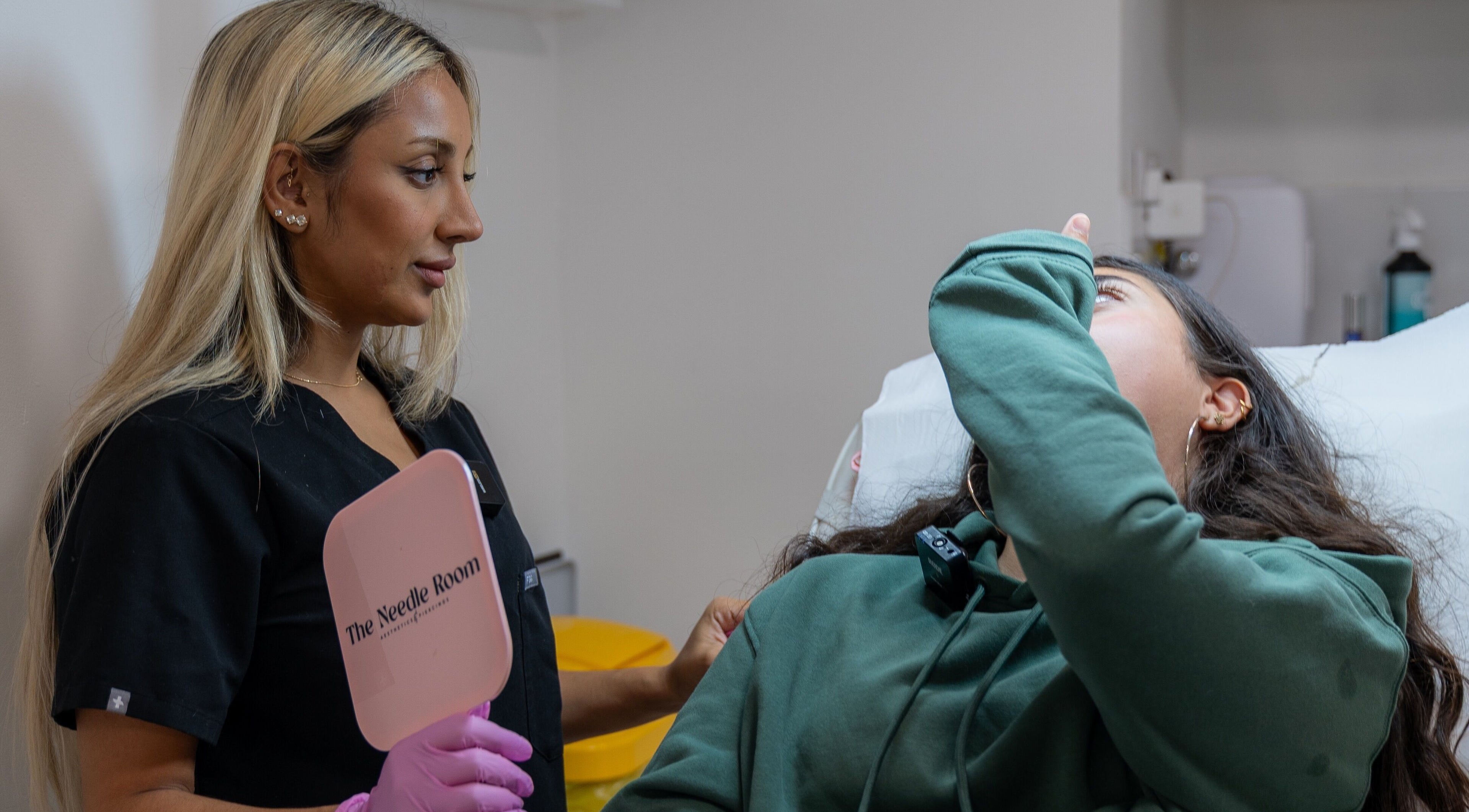 Practitioner consulting client at The Needle Room, London, England, GB, holding branded mirror.