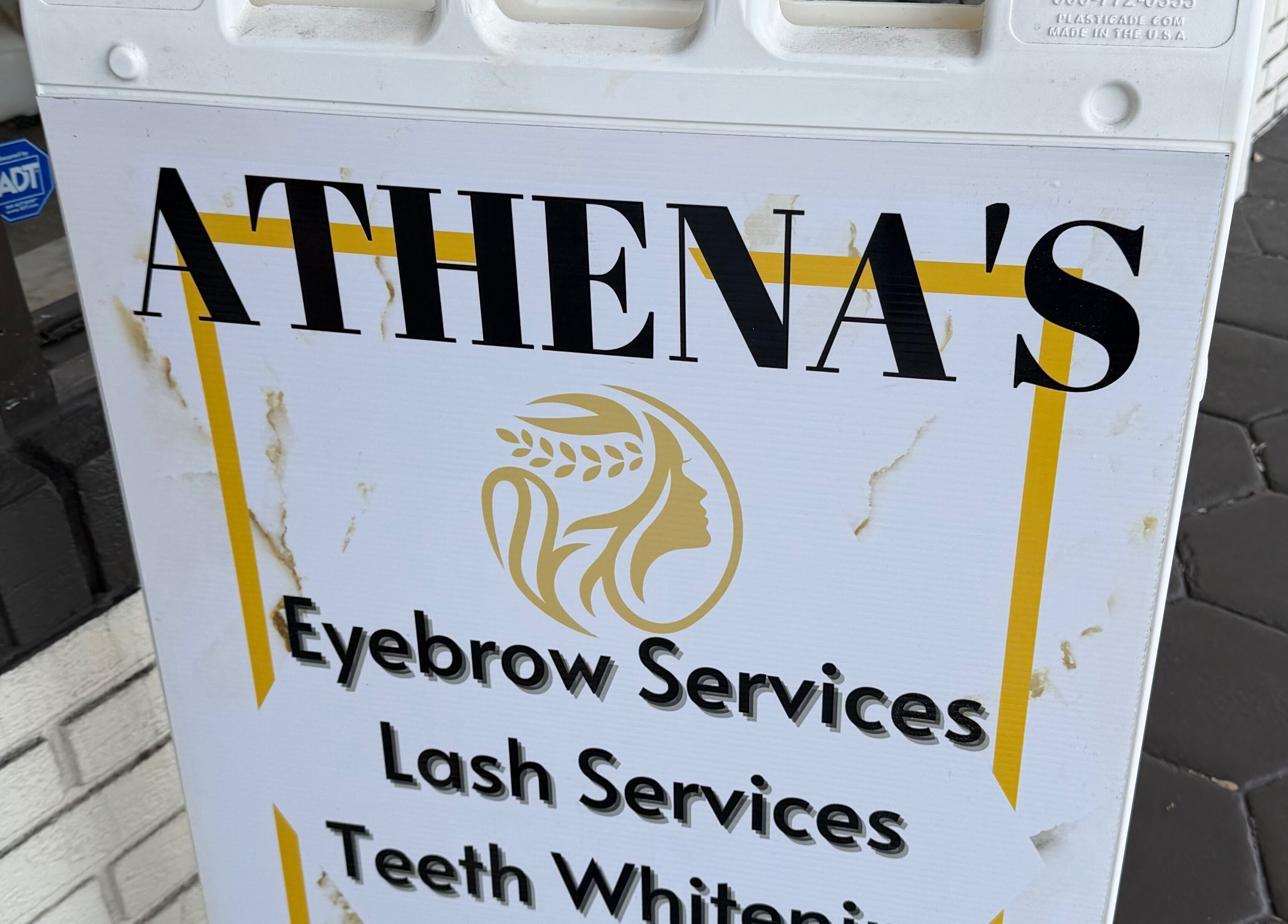 Signboard of Athenas Aesthetics in Hollywood, Florida, US offering eyebrow, lash, and teeth whitening services.