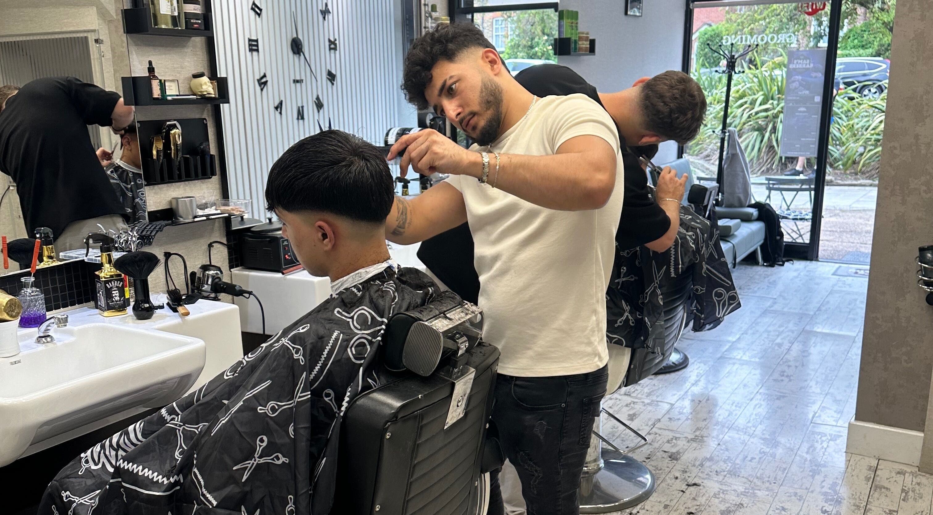 Barber styling hair at Sam’s Barbers London, located in London, England, GB, with modern interior.