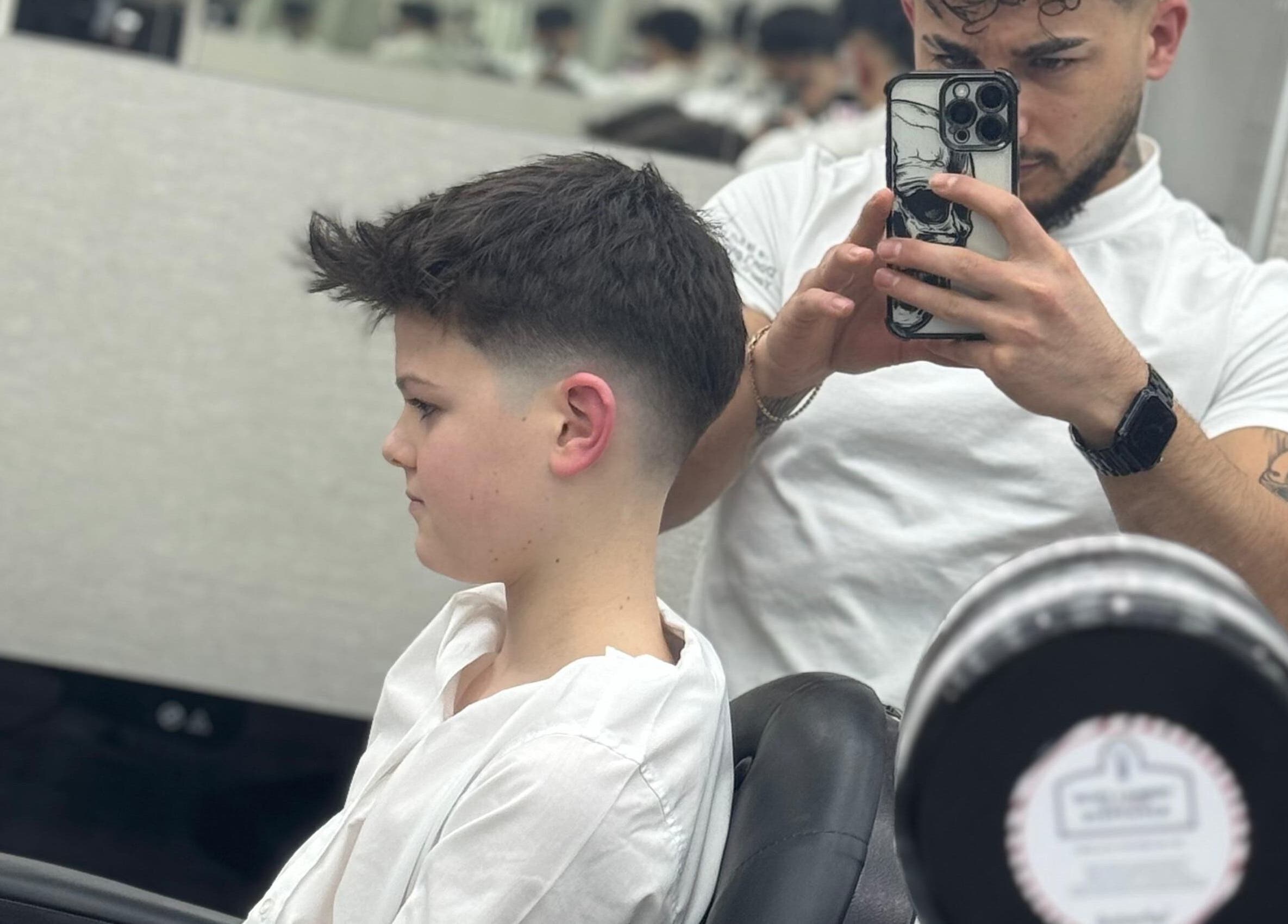 A barber giving a stylish haircut at Sam’s Barbers London, located in London, England, GB.