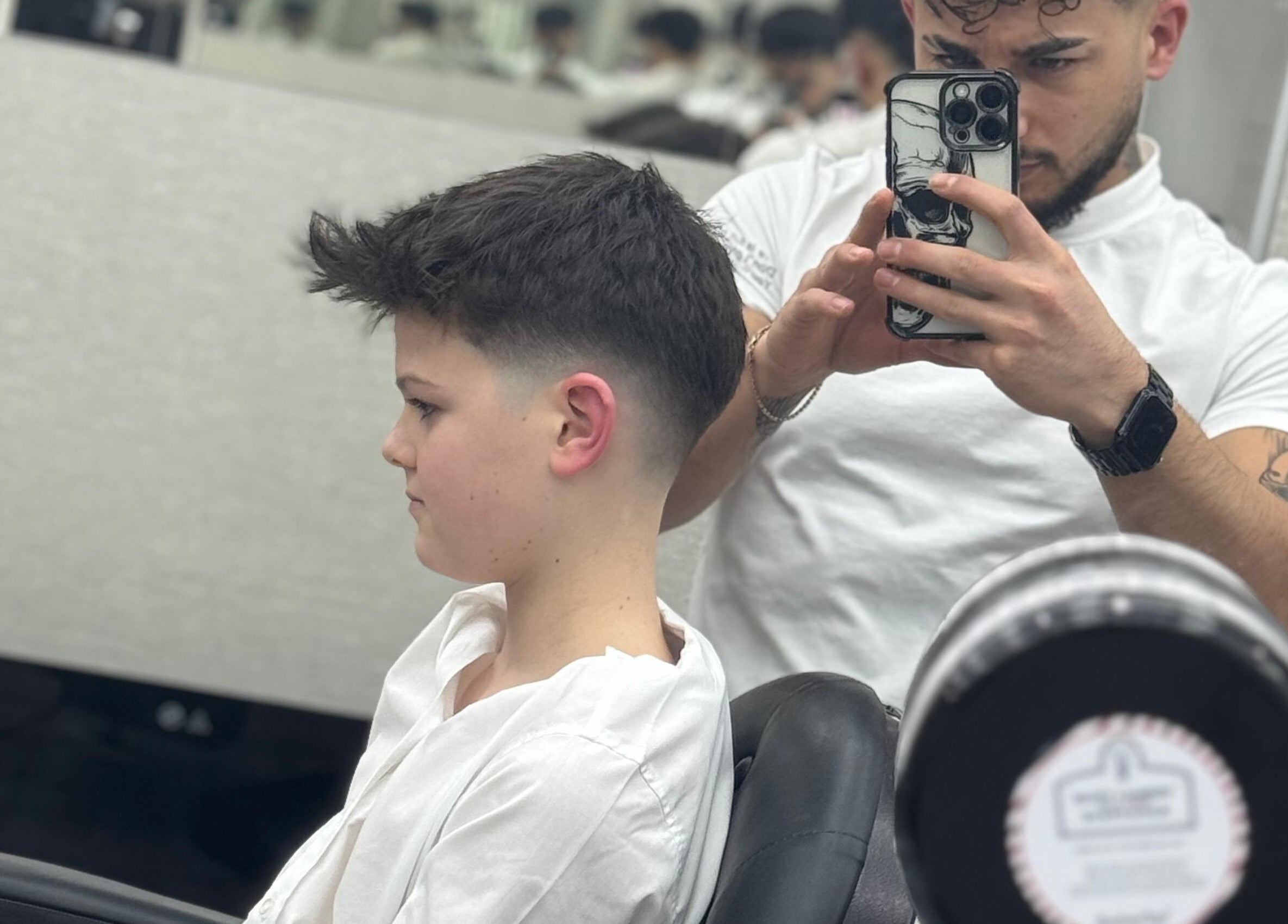 A barber giving a stylish haircut at Sam’s Barbers London, located in London, England, GB.