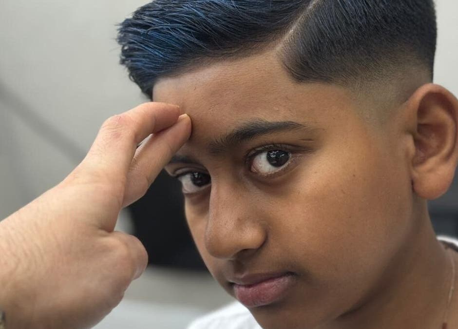 Young boy receiving a stylish haircut at Sam’s Barbers London, located in London, England, GB.