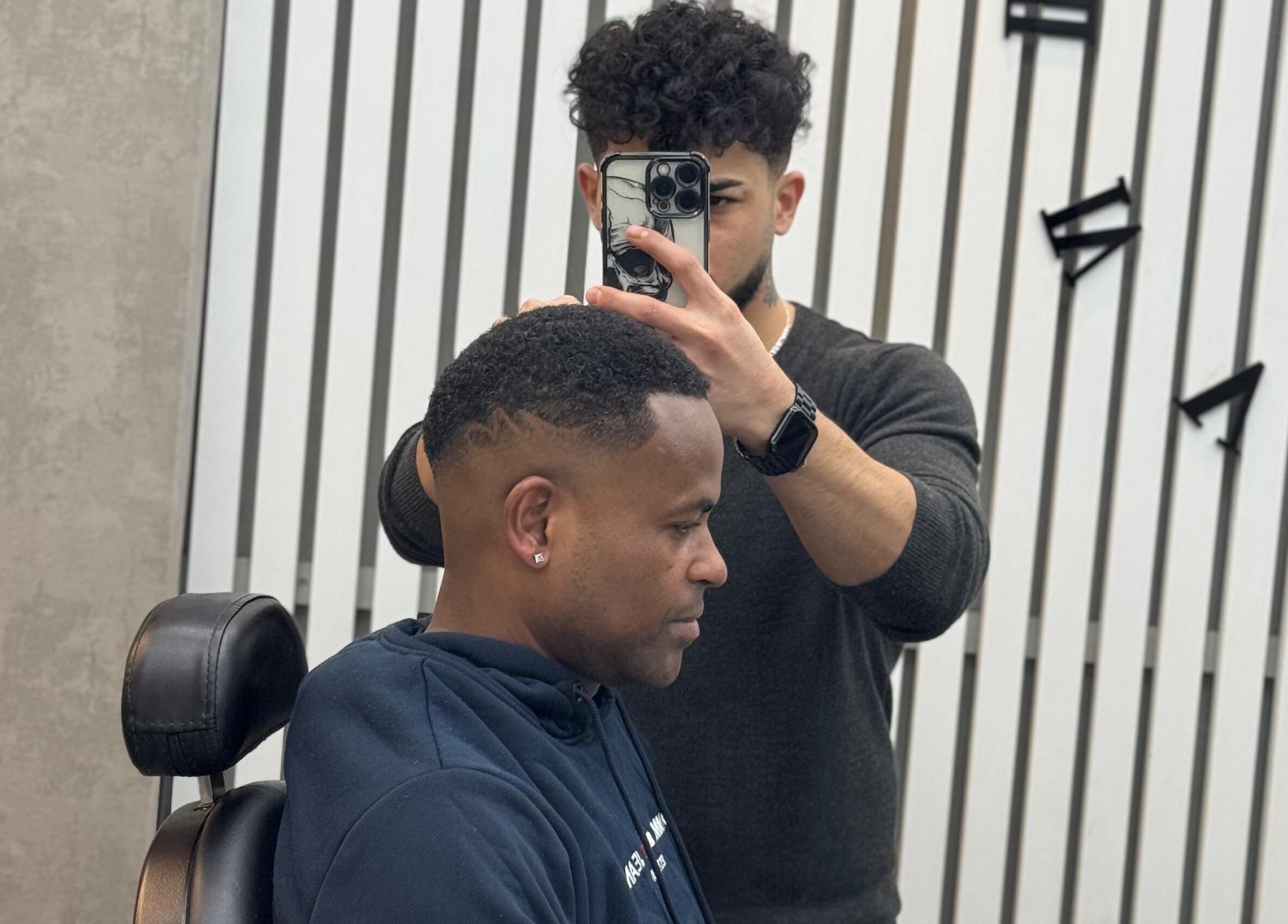 A barber at Sam’s Barbers London styling a man's hair, London, England, GB.