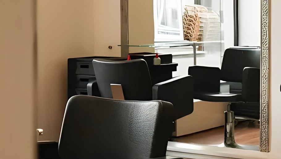 Modern black salon chair at Kukyan Hair Bar, Rīga, LV, highlighting a chic and comfortable setting.