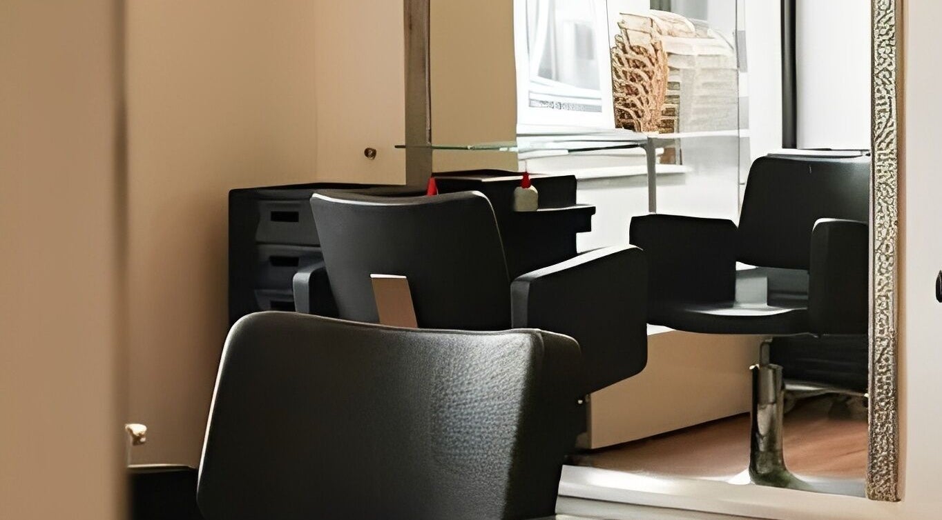 Modern black salon chair at Kukyan Hair Bar, Rīga, LV, highlighting a chic and comfortable setting.