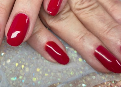 Ongles rouges éclatants chez Nail's Beauty, Mios, Nouvelle-Aquitaine, FR, sur fond scintillant.
