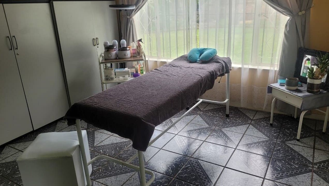 Tranquil treatment room with a massage bed at DeBeauté in Kempton Park, Gauteng, ZA, bathed in natural light.