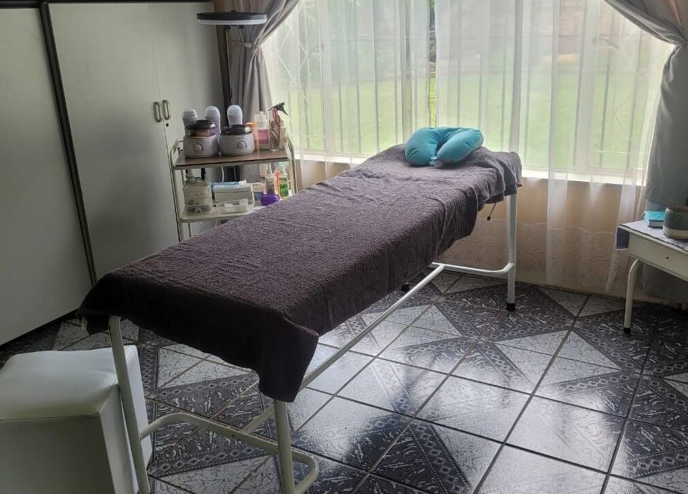 Tranquil treatment room with a massage bed at DeBeauté in Kempton Park, Gauteng, ZA, bathed in natural light.