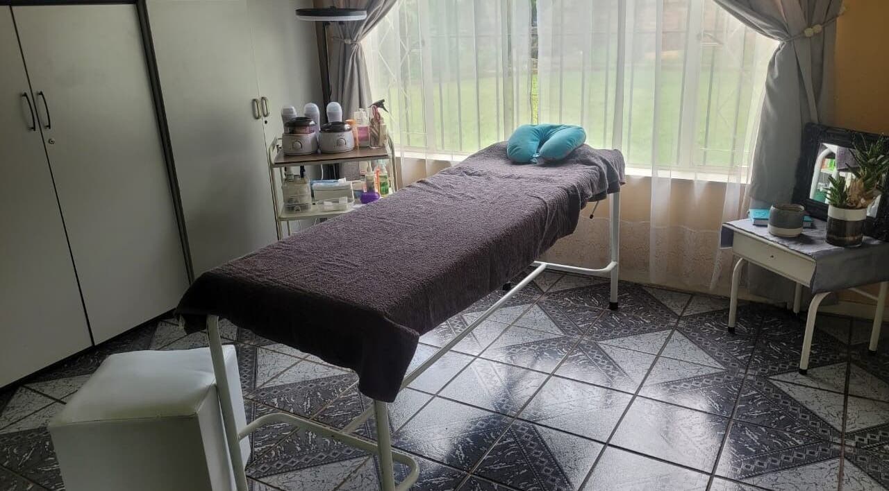 Tranquil treatment room with a massage bed at DeBeauté in Kempton Park, Gauteng, ZA, bathed in natural light.