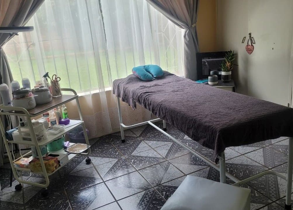 A serene treatment room at DeBeauté, Kempton Park, Gauteng, ZA, featuring a comfortable massage table near a window.