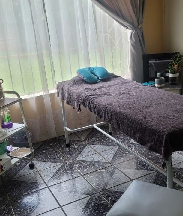 A serene treatment room at DeBeauté, Kempton Park, Gauteng, ZA, featuring a comfortable massage table near a window.
